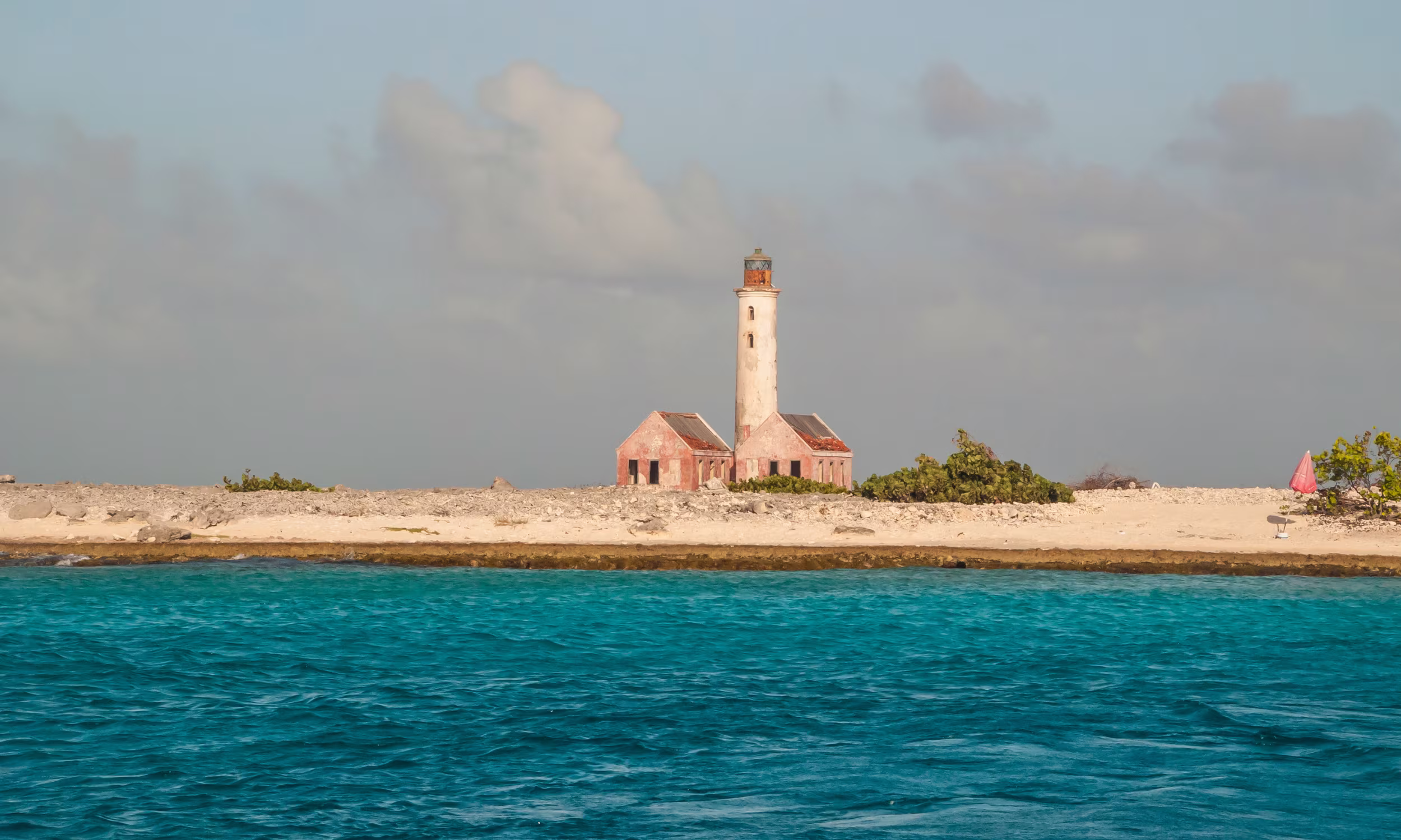Lighthouse on Curaçao’s north coast with blue sea and arid landscape. 