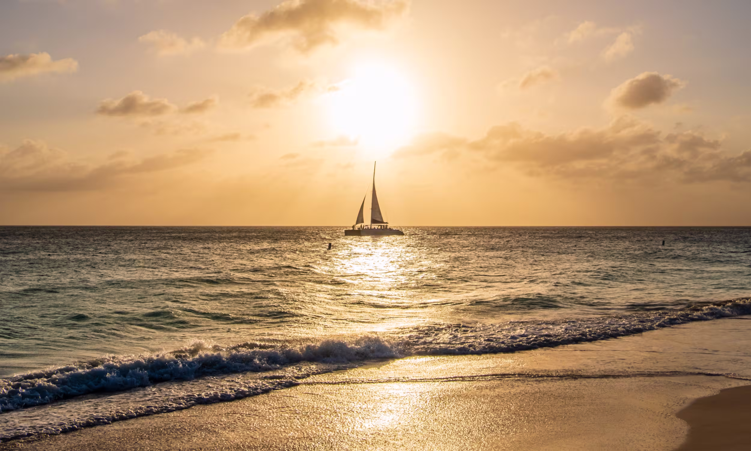 Sailboat at sunset over calm Caribbean waters in Aruba. 