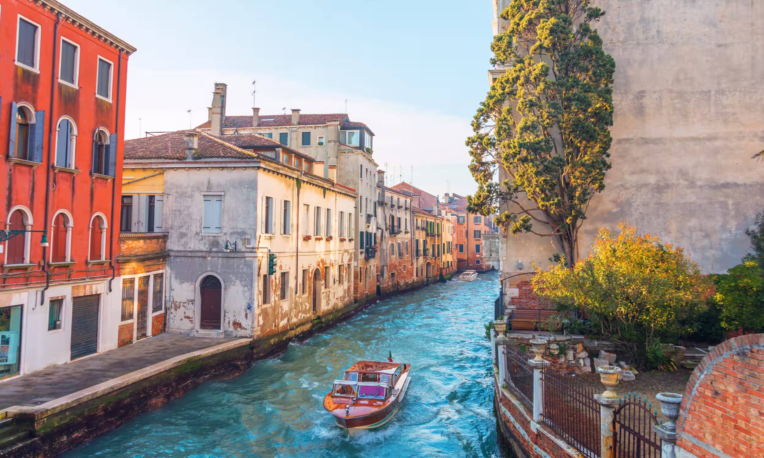Venice canals with a gondola and colorful houses reflected in the water. 
