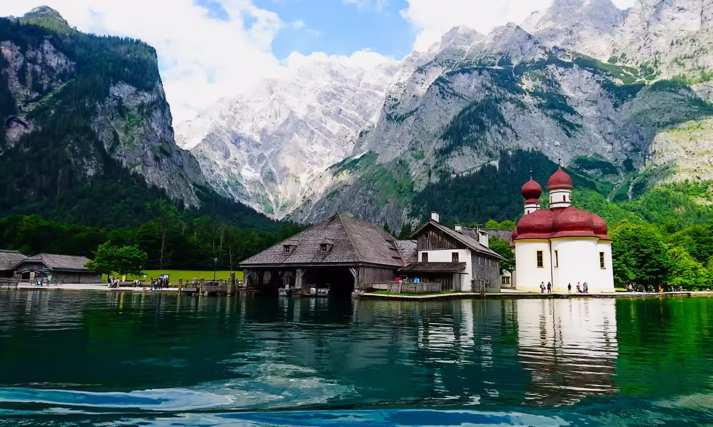 Lake Königssee with St. Bartholomä Church surrounded by alpine mountains. 