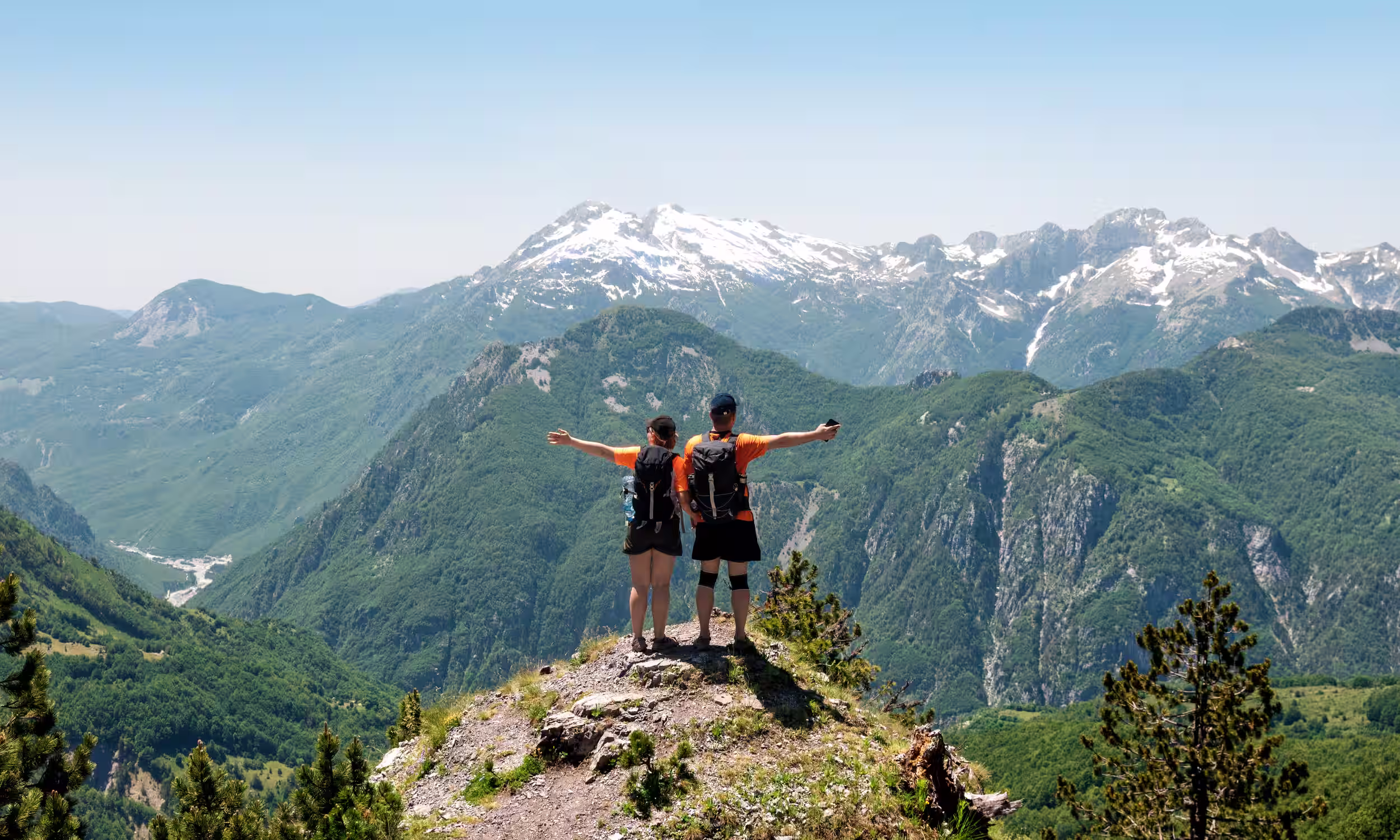 Couple on a mountaintop in Northern Albania with panoramic views — adventurous honeymoon destination. 
