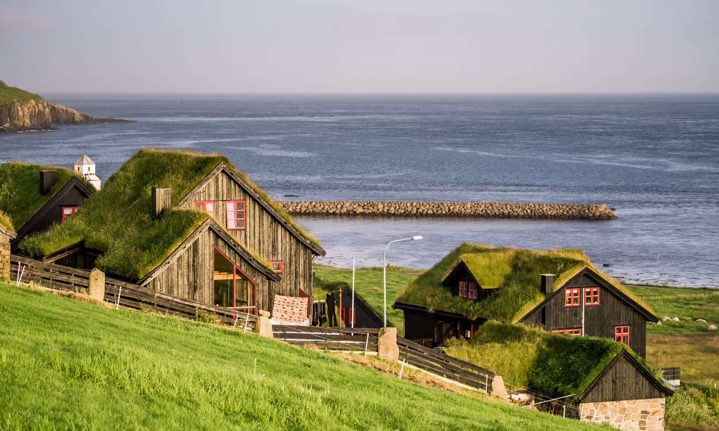 Scenic historic village of Kirkjubøur with green-roofed houses by the sea.