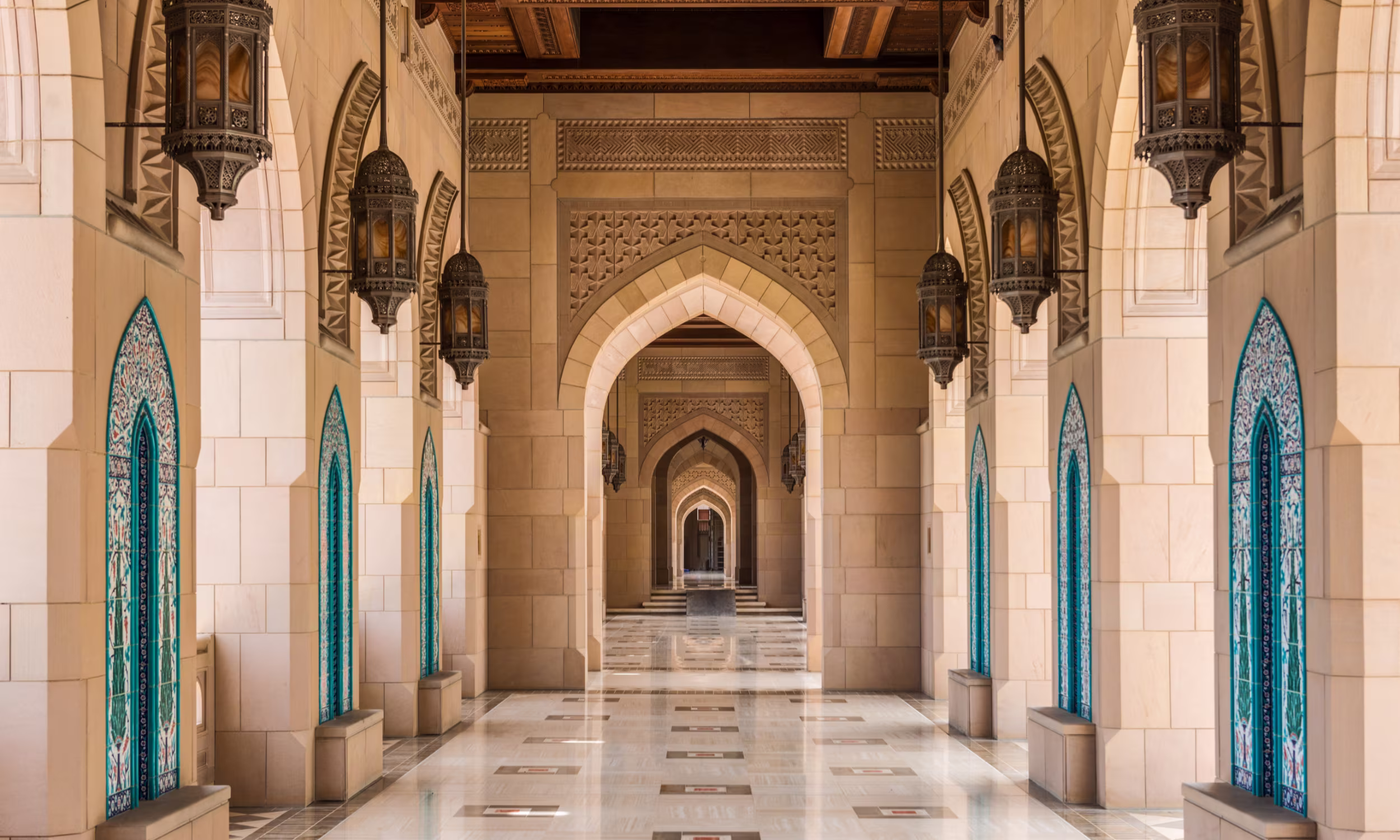 Marble and stone mosque with ornate arches and blue doors.