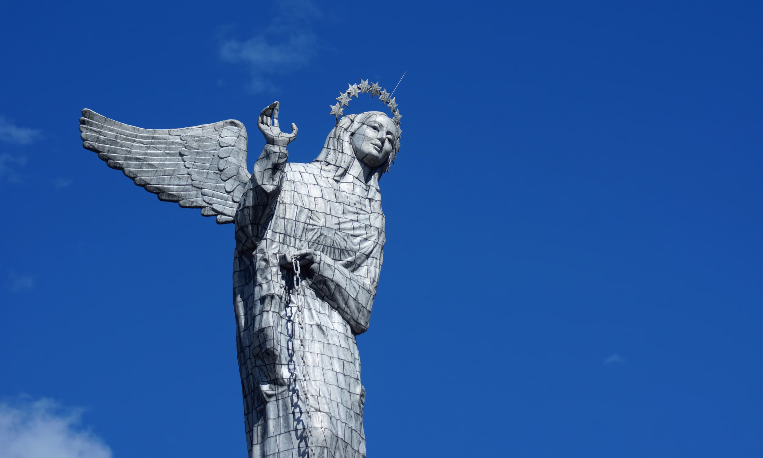 Winged Virgin of Quito statue against clear blue sky. 