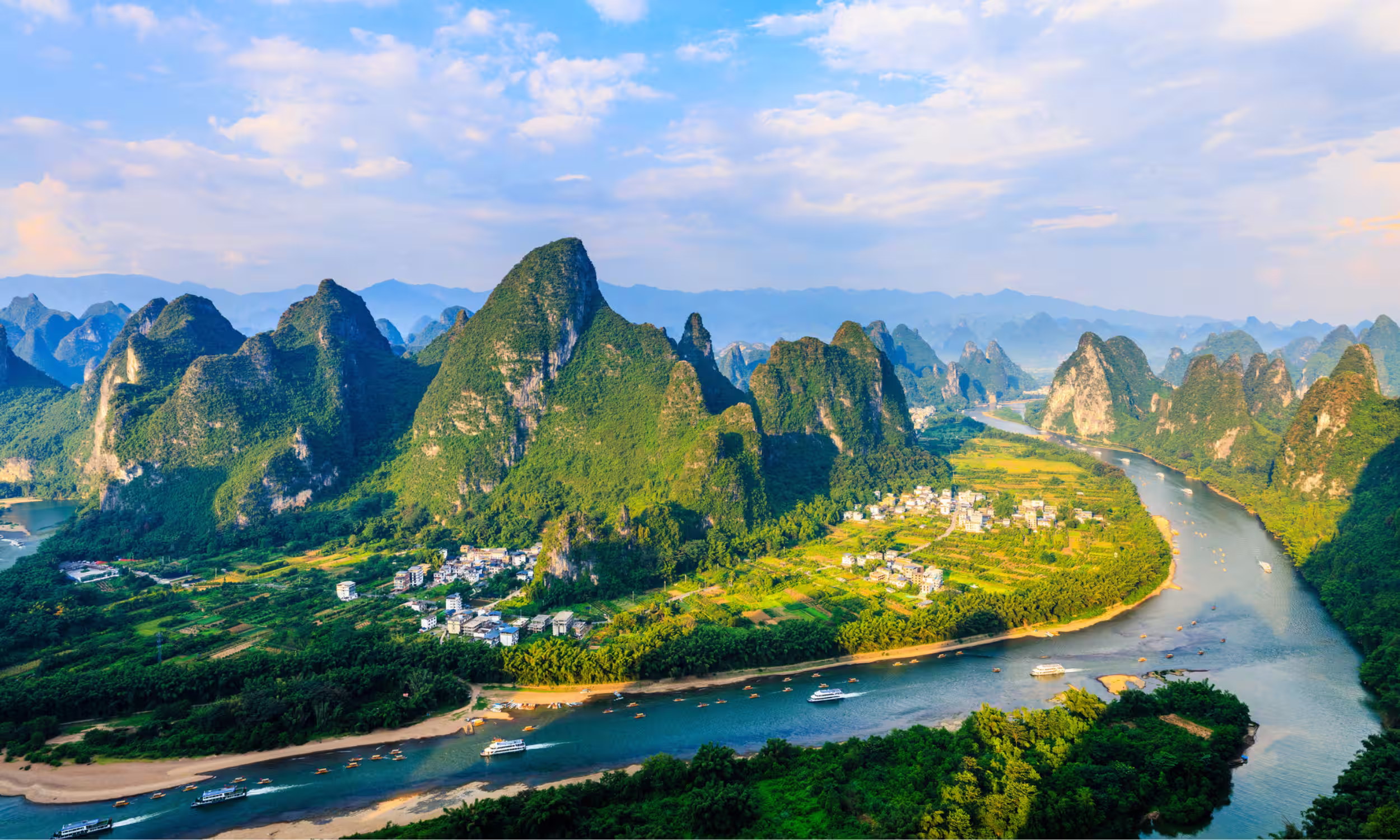 Paisagem montanhosa na China com rio a serpentear por um vale verde.