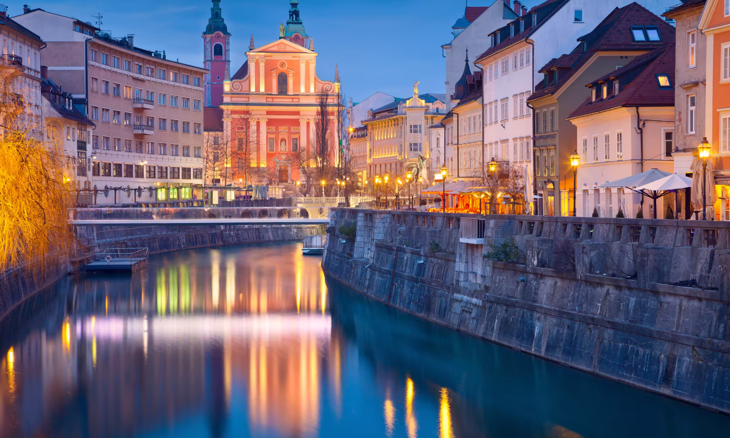 Ljubljana city during blue hour, with lights reflecting on the river and a romantic evening atmosphere.