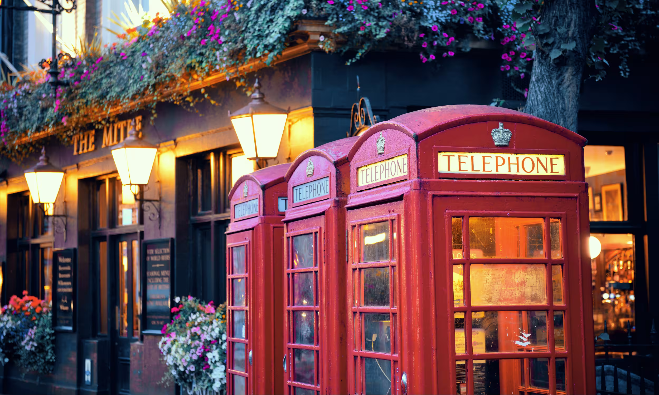 Rua típica de Londres com cabine telefónica vermelha e ambiente urbano tradicional.