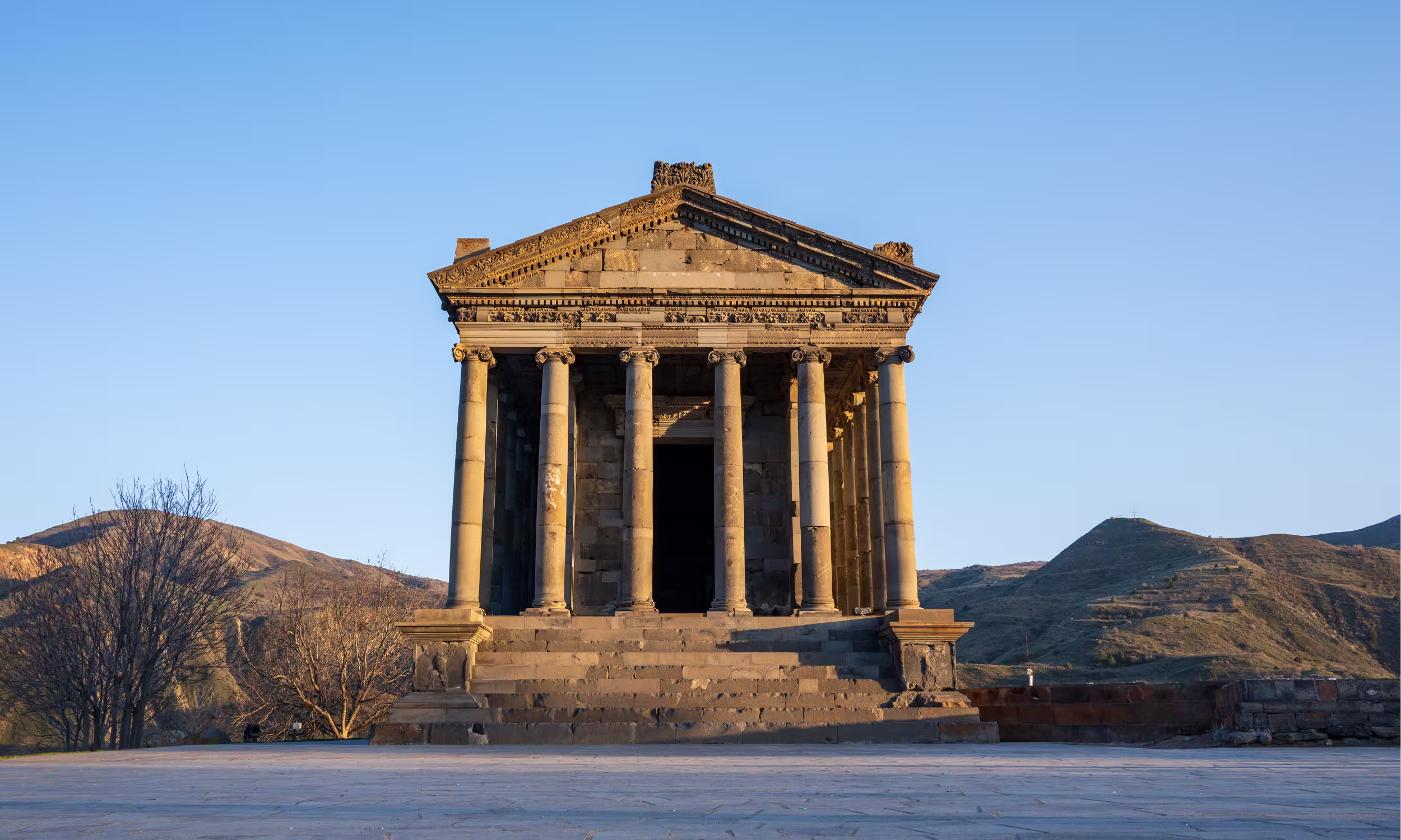 Templo de Garni com colunas clássicas rodeado por paisagem coberta de neve.