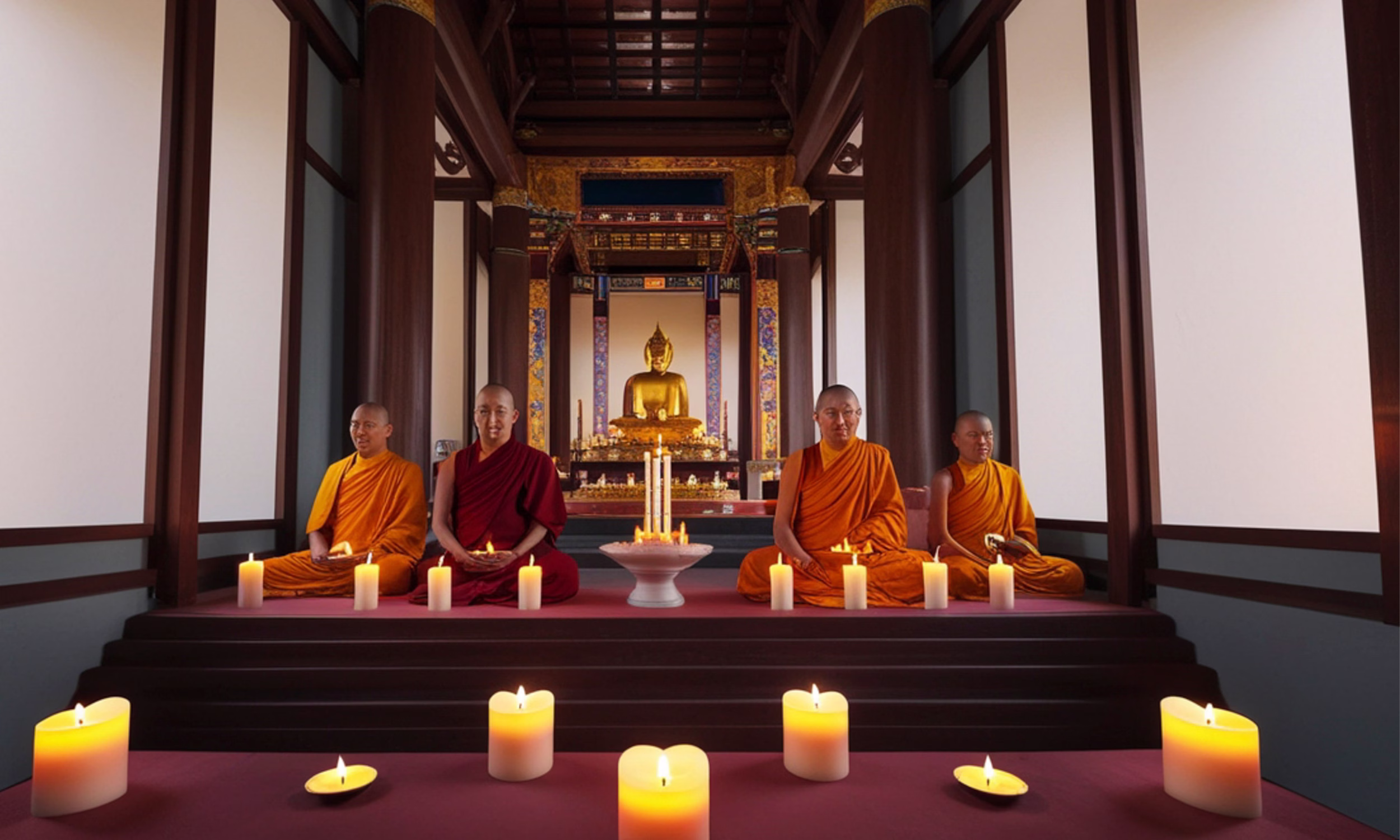 Monges budistas a meditar à luz de velas num templo em Chiang Mai.