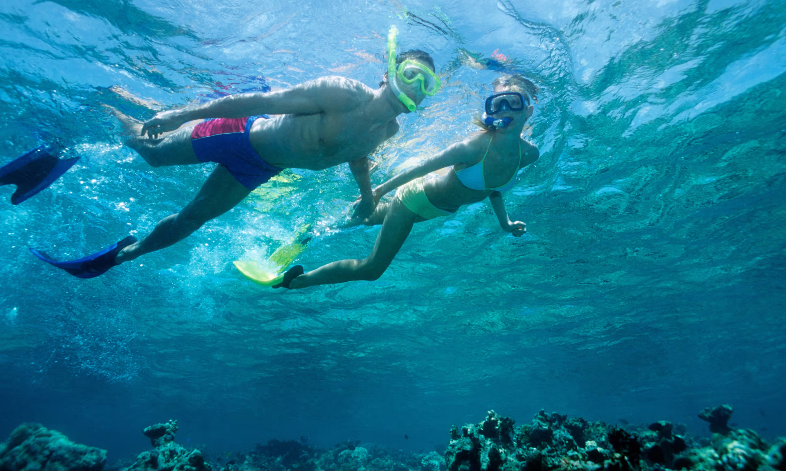 Casal a fazer snorkeling nas águas cristalinas de Saint Martin, rodeado por vida marinha colorida.