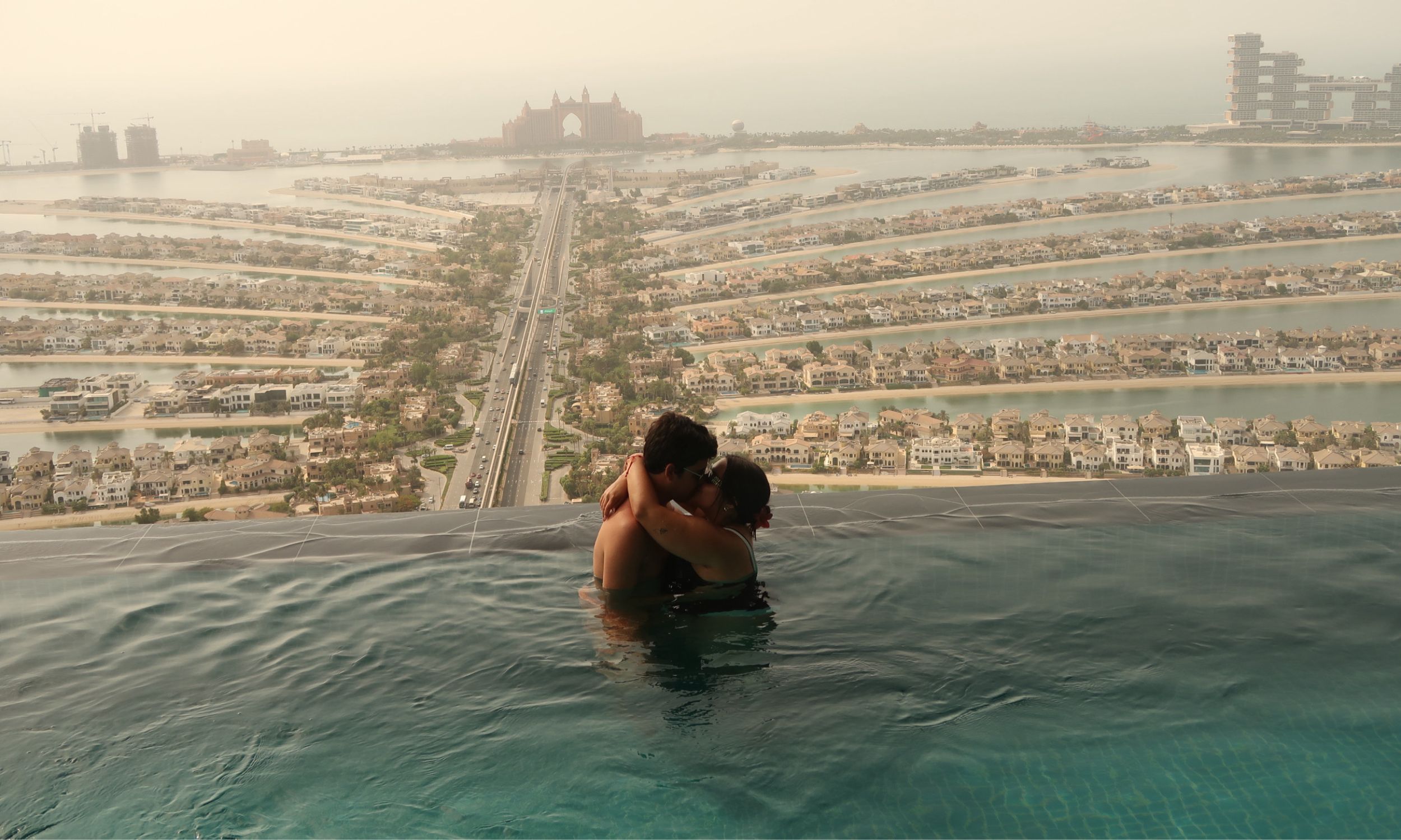 Casal em lua de mel na Palm Jumeirah, no Dubai, junto a uma piscina infinita com vista para o Atlantis e para a icónica ilha artificial.