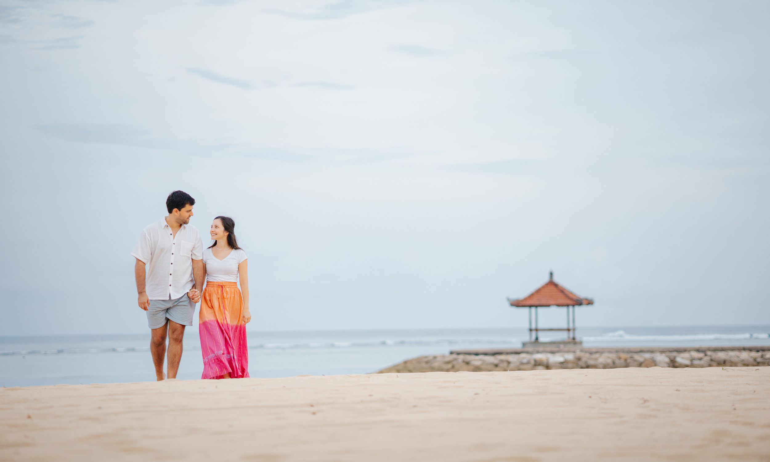 Honeymooners couple walking hand in hand along a beach in Indonesia during their customized honeymoon.