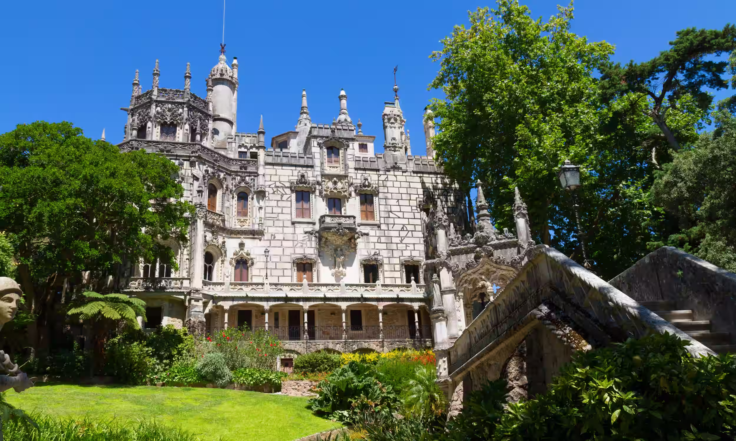 Quinta da Regaleira in Sintra surrounded by lush gardens and romantic architecture.