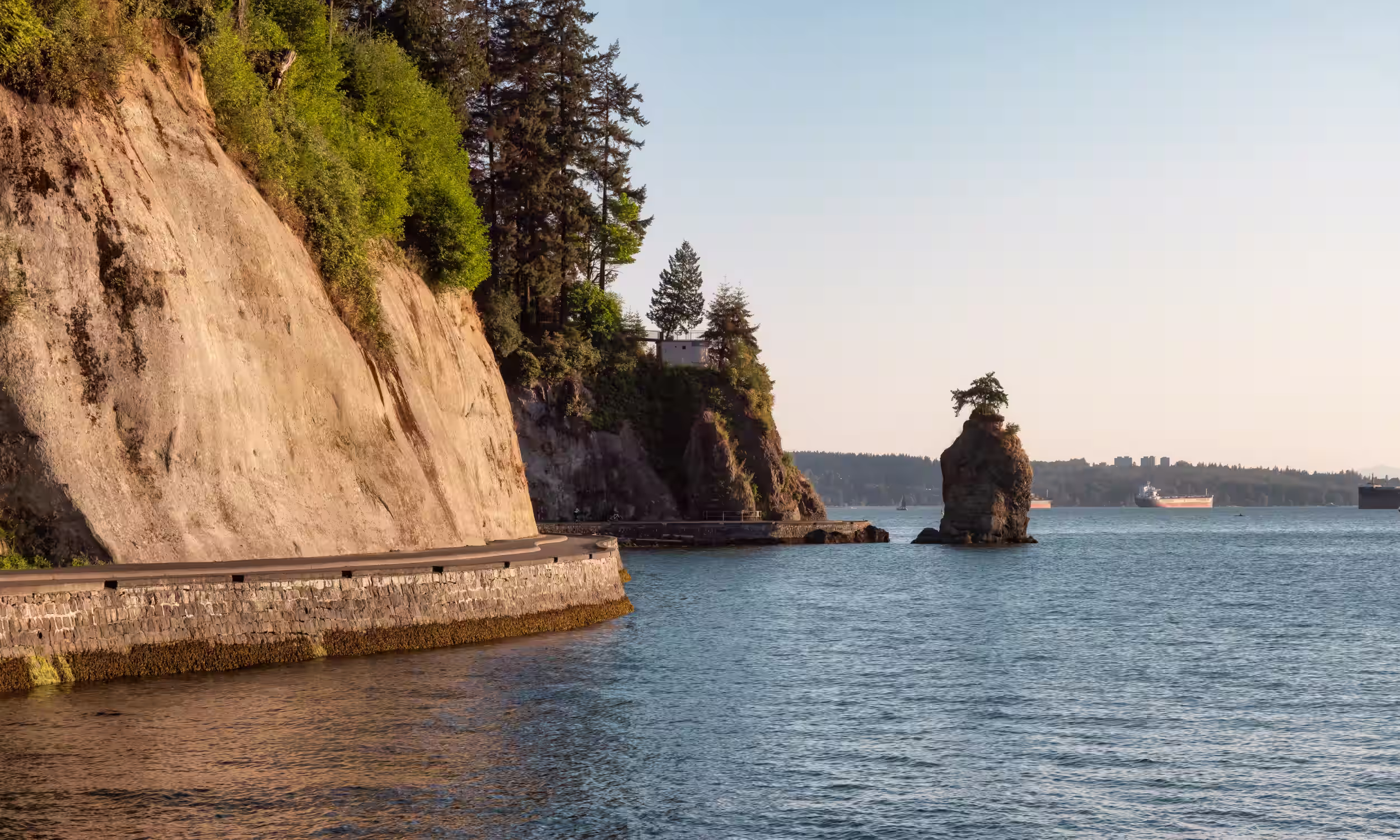 Seawall de Stanley Park junto ao Pacífico, em Vancouver, rodeada pela paisagem costeira e pela floresta.