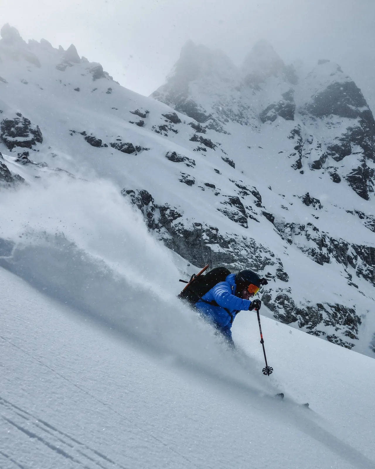 Skier making a powder turn below jagged peaks in the Silvretta Alps