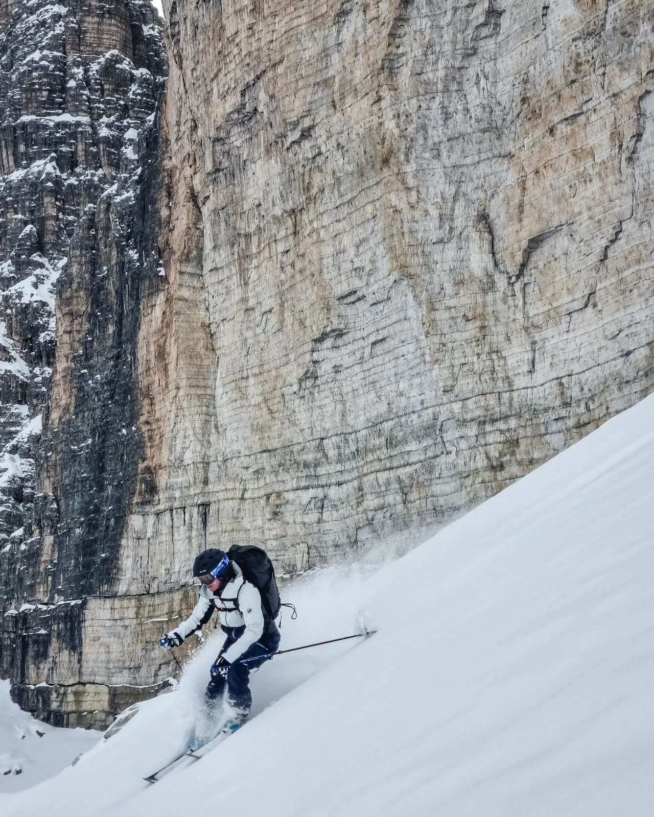 Skier descending beneath the massive rock walls of the Tre Cime di Lavaredo