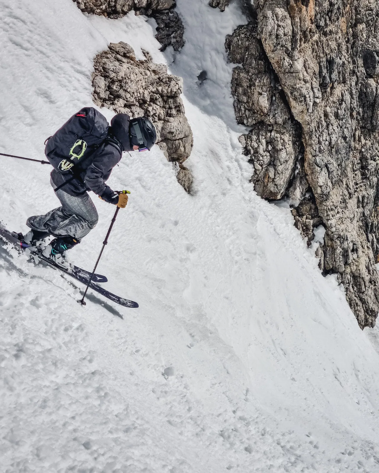 Skier descending a narrow, steep couloir between rock walls