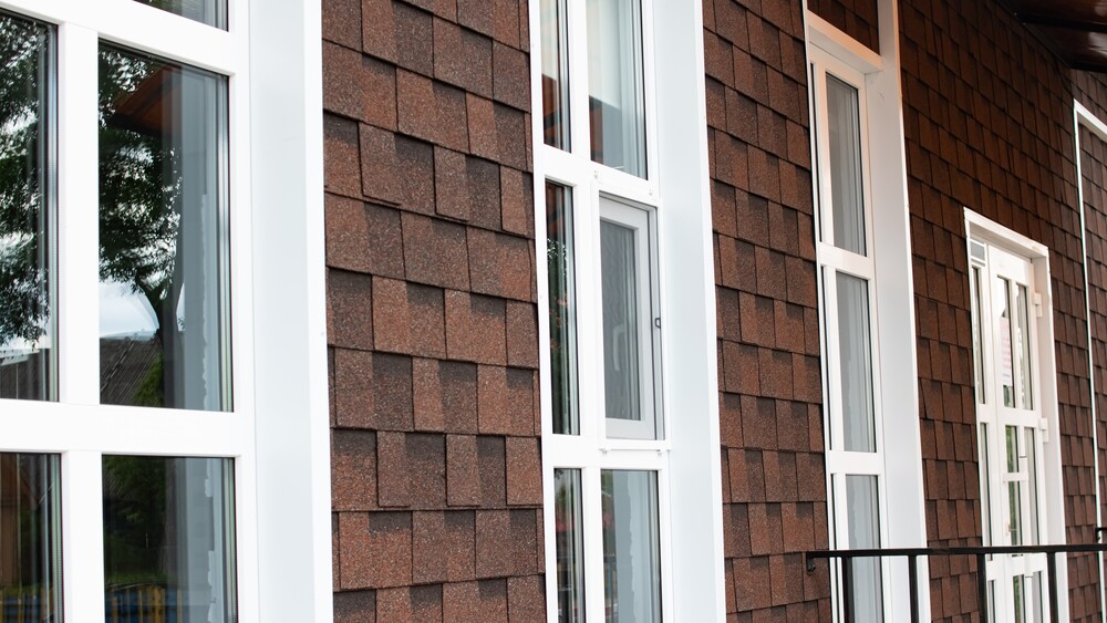 Side view of home with red siding and white framed replacement windows