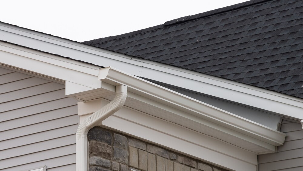 Close-up view of white gutter, fascia, and downspout