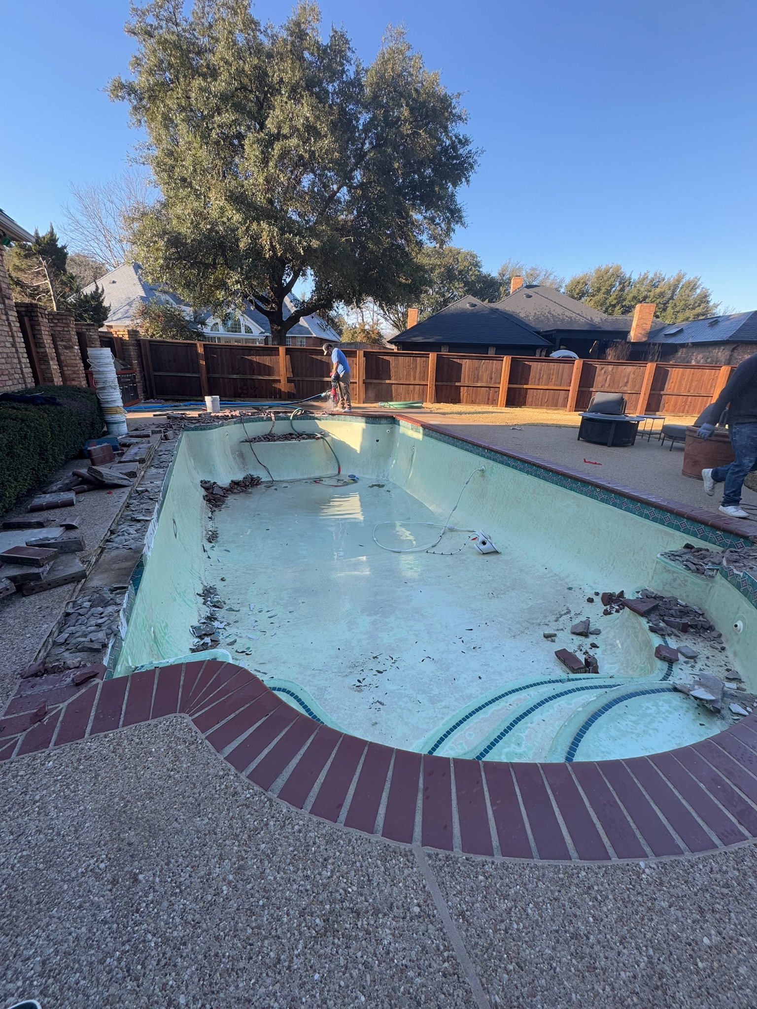 Drained pool during demolition with old brick coping being removed