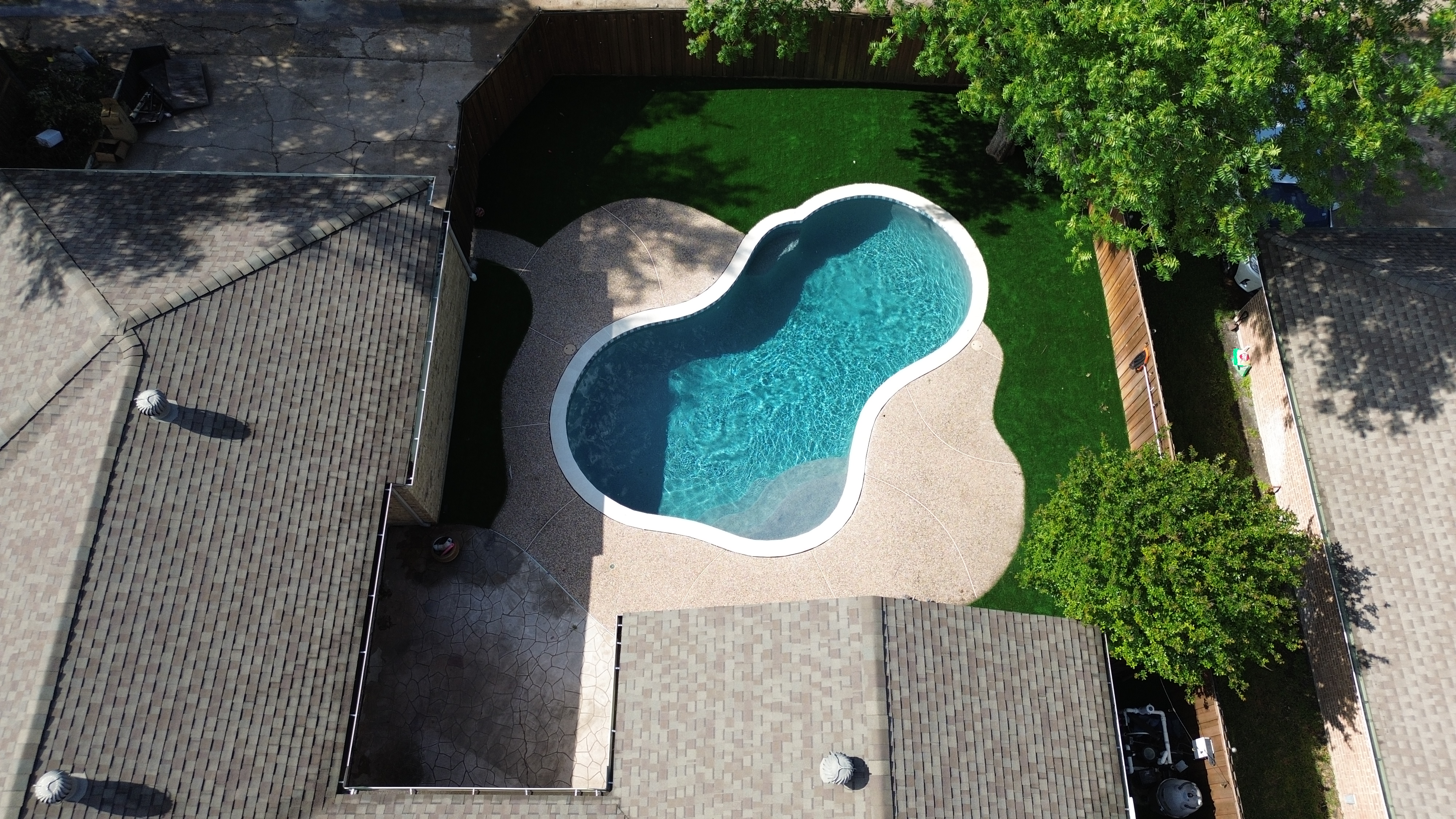 Restored kidney-shaped pool with clear blue water, aerial view