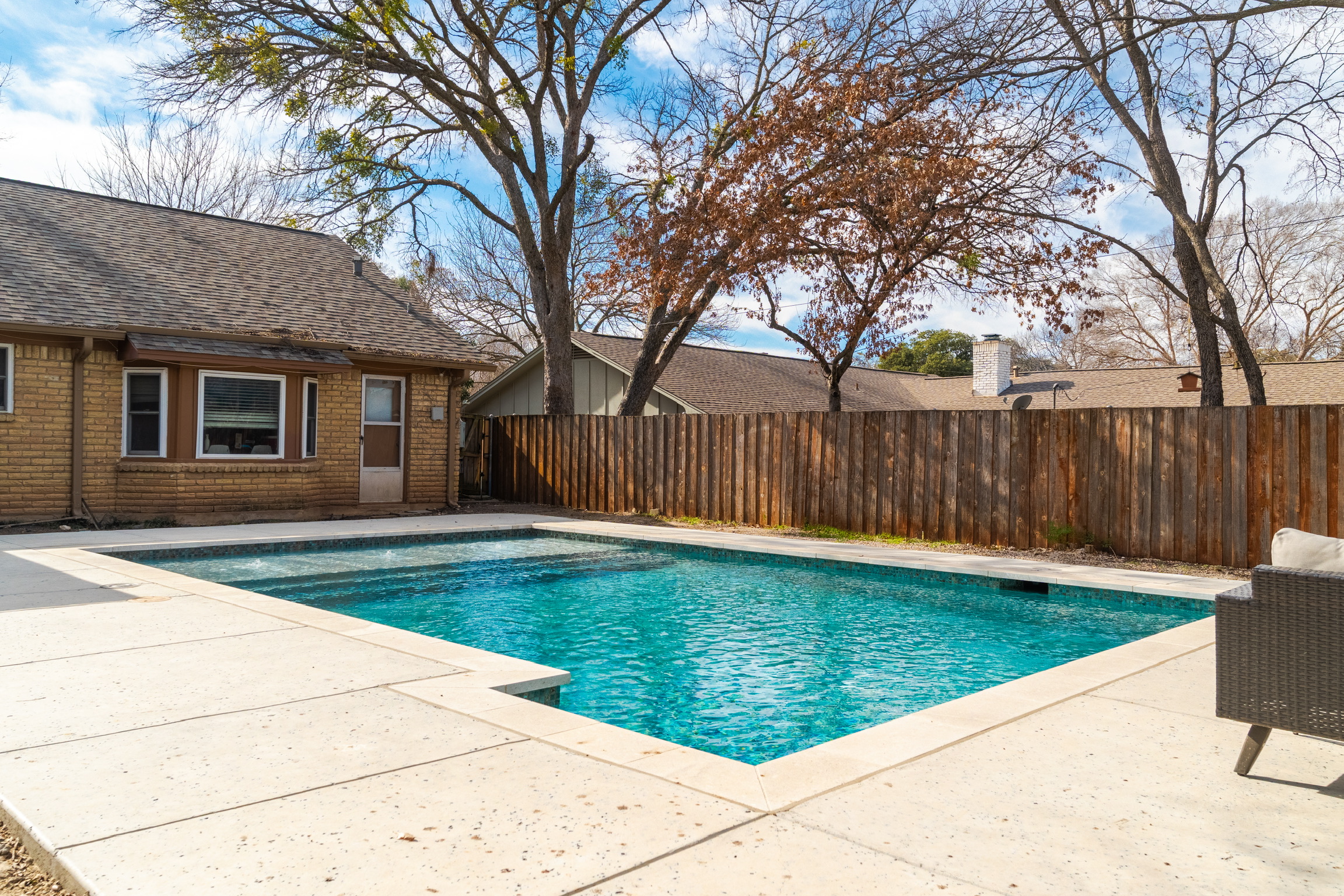 Rectangular plaster pool with glass waterline tile, view toward the house