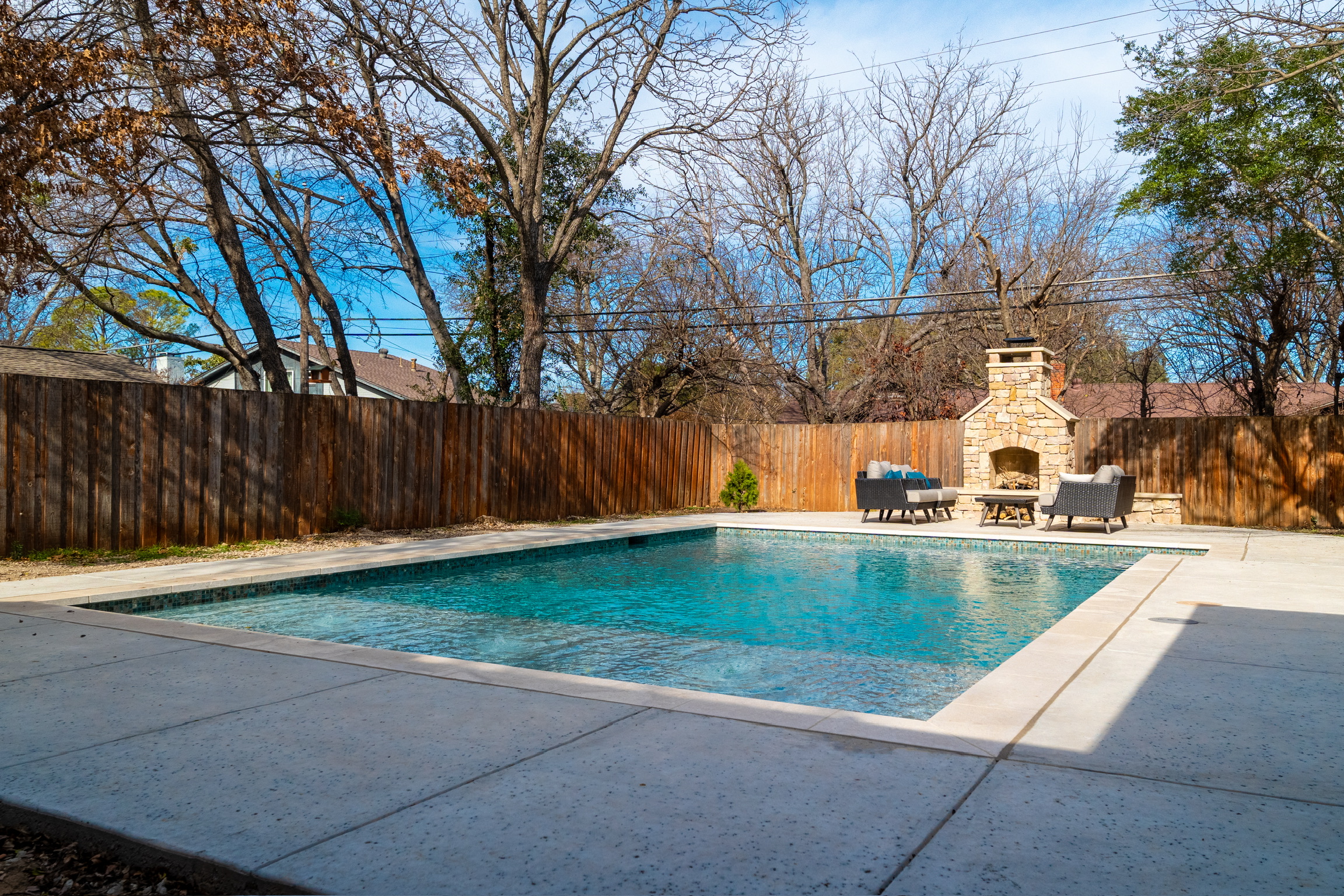 Plaster pool with glass tile and stacked-stone fireplace