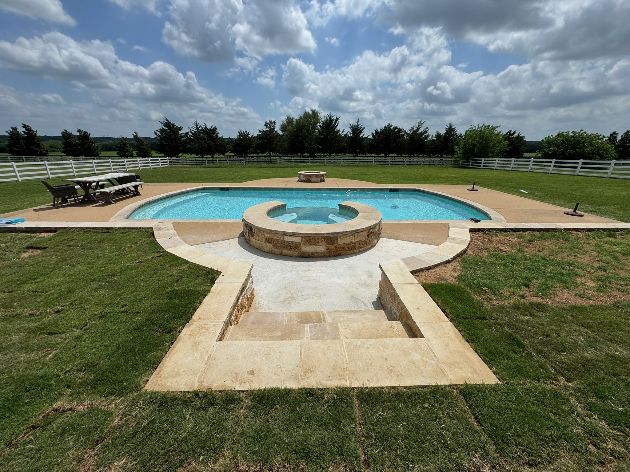 Finished backyard with centered stone walkway and steps leading to the spa and pool
