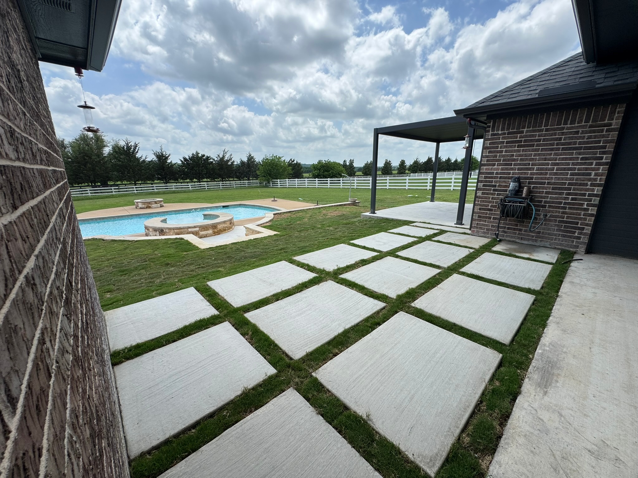 Concrete paver patio with grass joints looking toward the pool