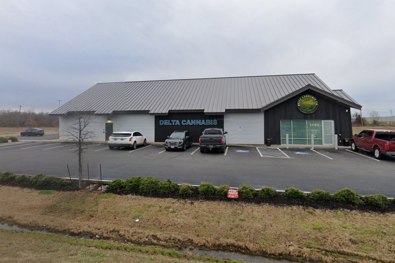 Delta Cannabis Co. dispensary storefront at 1151 E. Service Rd., West Memphis, Arkansas — exterior view of the black and white barn-style building with metal roof, blue Delta Cannabis signage, and ample parking.