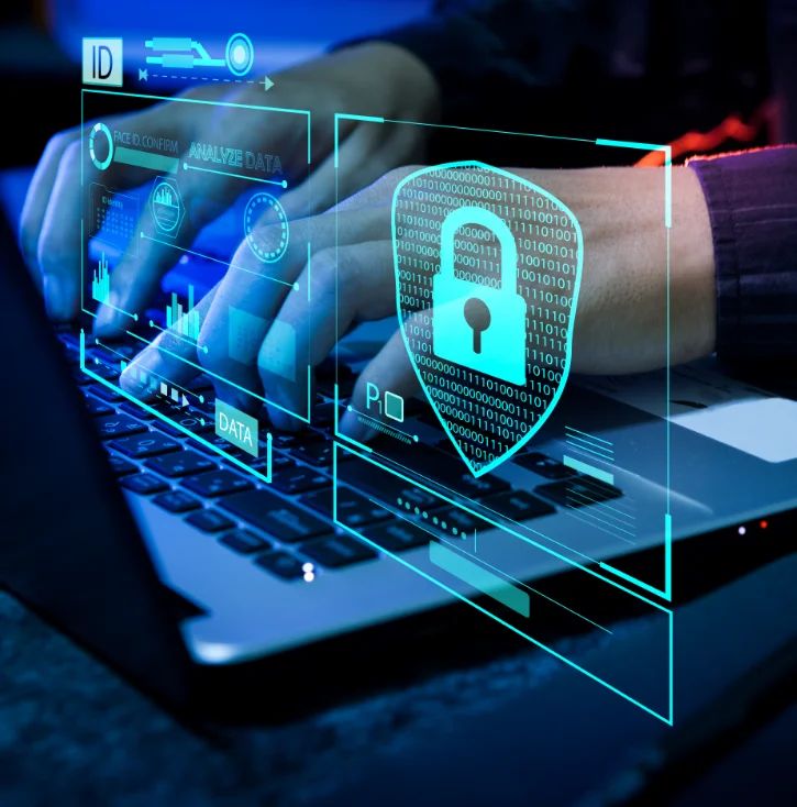Hands typing on a laptop beneath a holographic security shield and padlock, representing protected endpoint devices