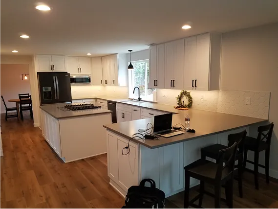 A finished modern kitchen in Tacoma featuring white cabinets, a large island, and light wood flooring.