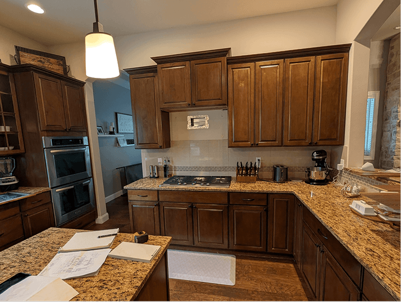 Cooking wall showing gas cooktop dropped into dark granite counter with double wall ovens on the right