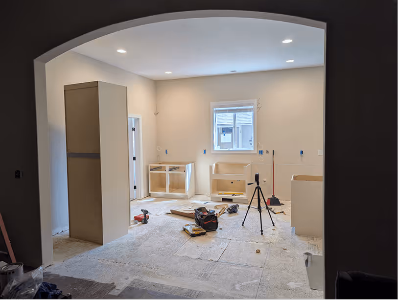 View through arched entry showing base cabinets on multiple walls and dark walnut island base taking shape