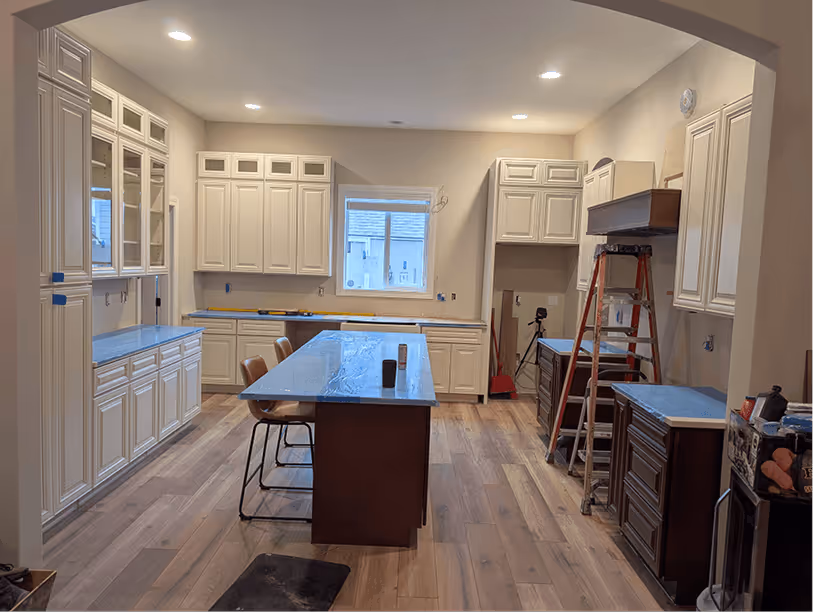 View from the living room through the arched entry showing the full two-tone cabinet layout and island