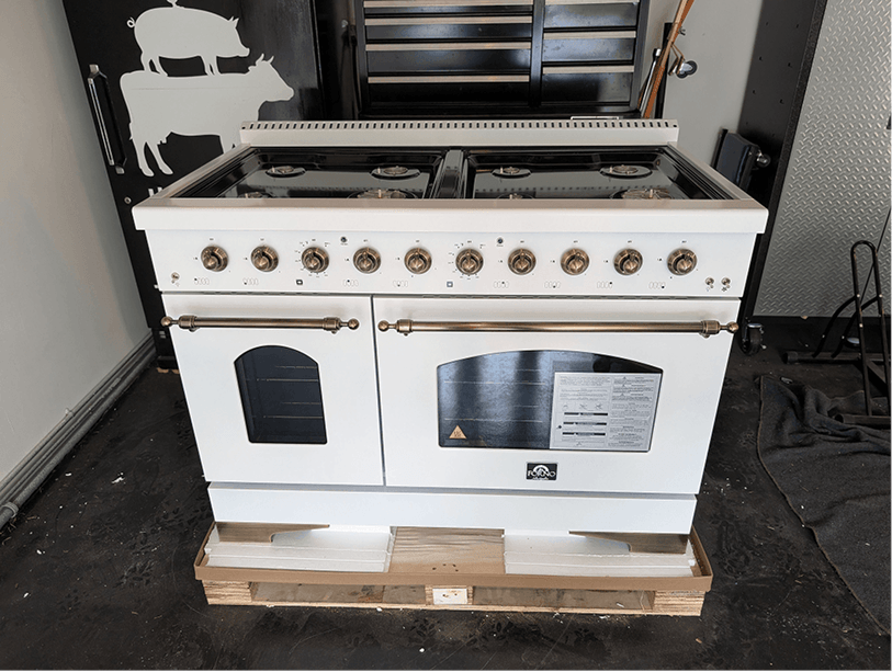 48-inch ILVE professional range on a shipping pallet with white enamel body, brass hardware, and six burners
