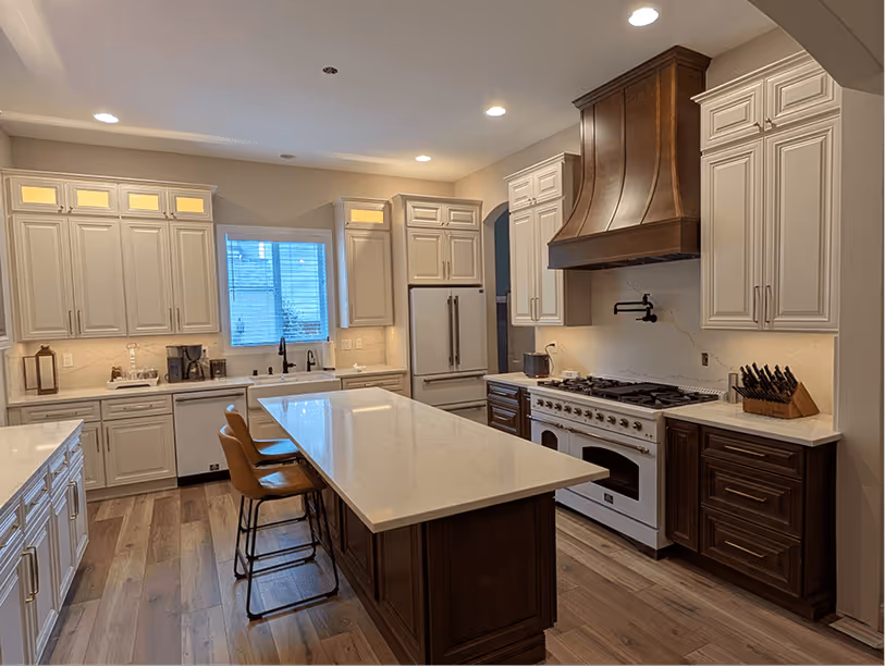 Full kitchen after remodel: white island, copper hood, ILVE range, pot filler, subway tile, and under-cabinet lighting