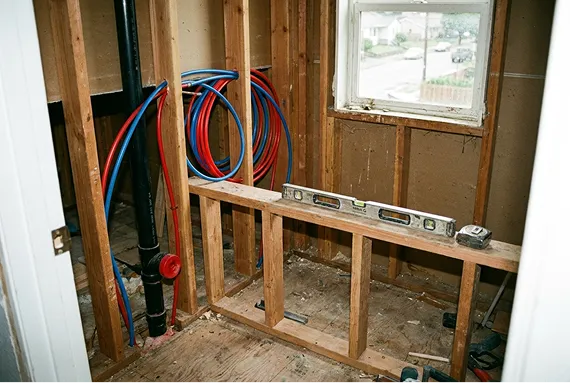 A Tacoma bathroom mid-remodel with the wall opened up and new plumbing rough-in visible.