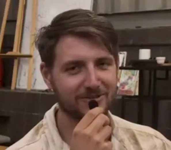 A man holding a piece of food in his mouth.