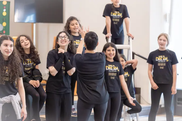 Ensemble cast performing live on stage during Cadenza's Dare to Dream musical theatre production