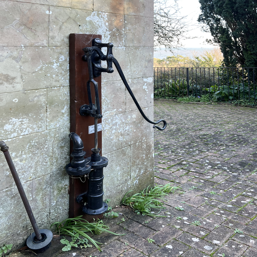 An period Victorian water pump mounted on an old stone wall
