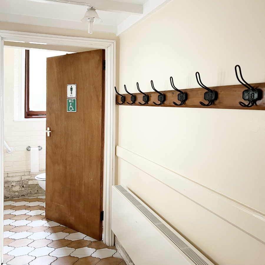 A tiled lobby leading to a door into the gent's toilets