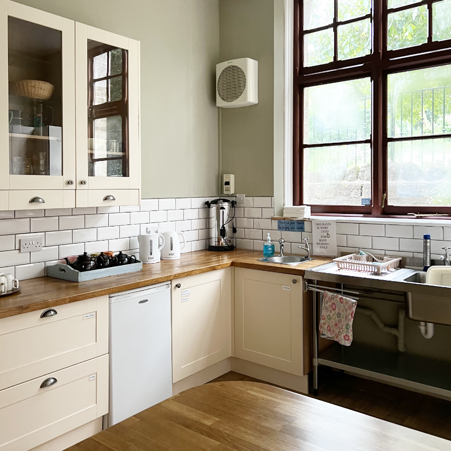 A traditional kitchen with green walls and cream shaker units
