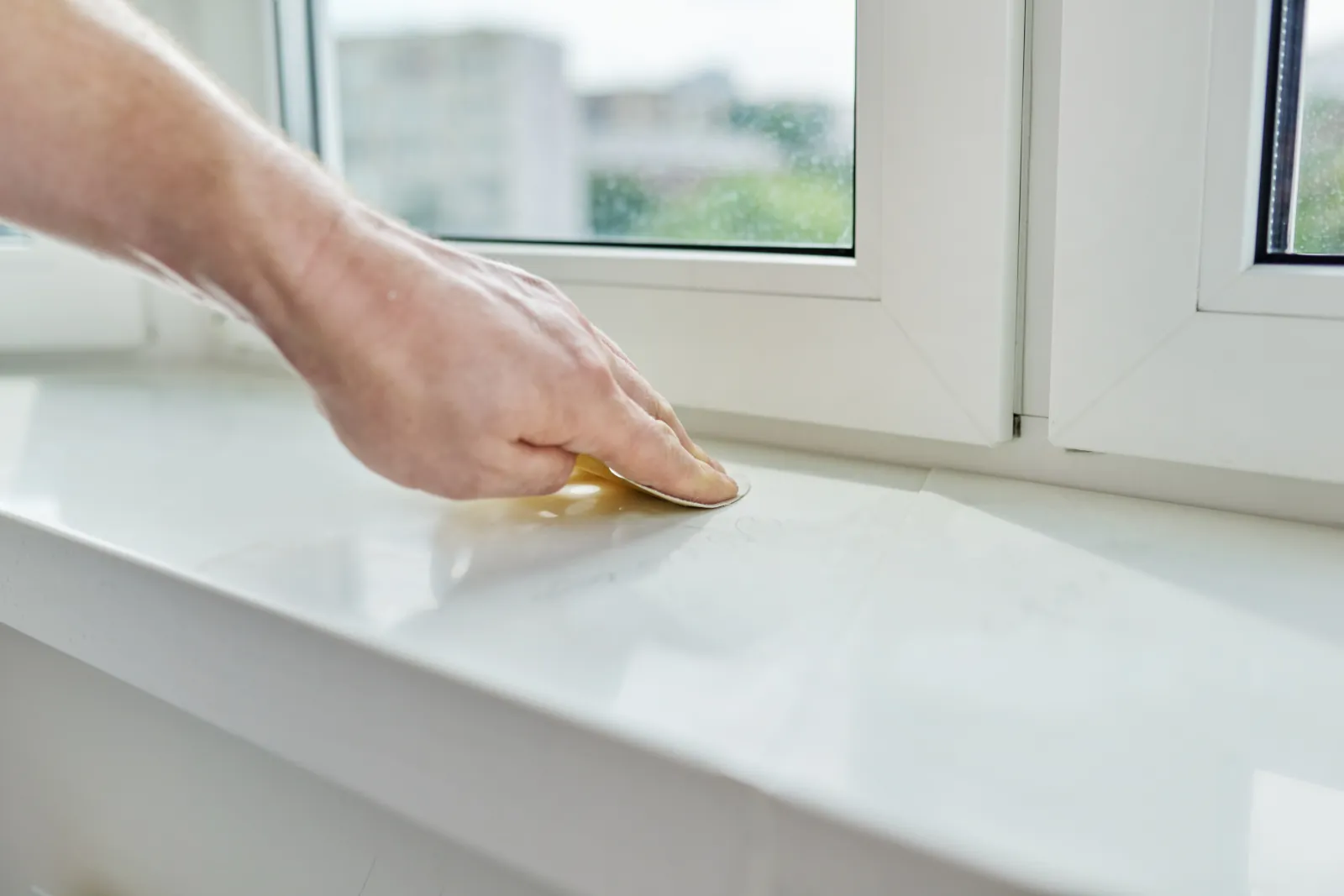 A homeowner in Bellevue sanding a window sill, one of the recommended repair options