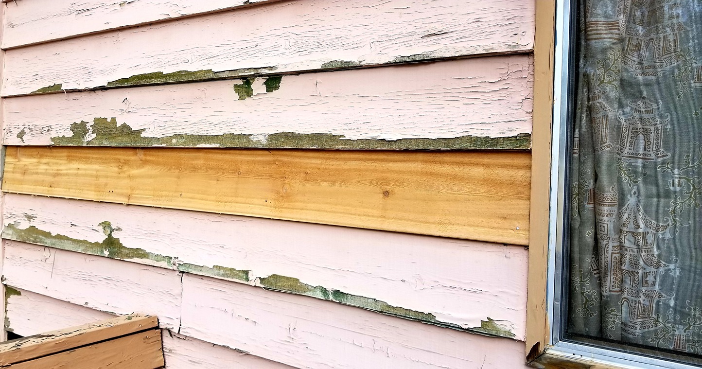 Exterior wall with peeling lap siding and exposed trim board near a window, showing weather damage and possible flashing repair area on a deck-side wall