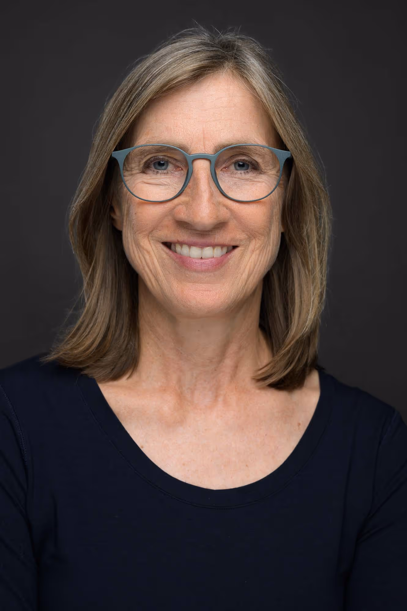 Eine Frau mit Brille und einem blauen Hemd.