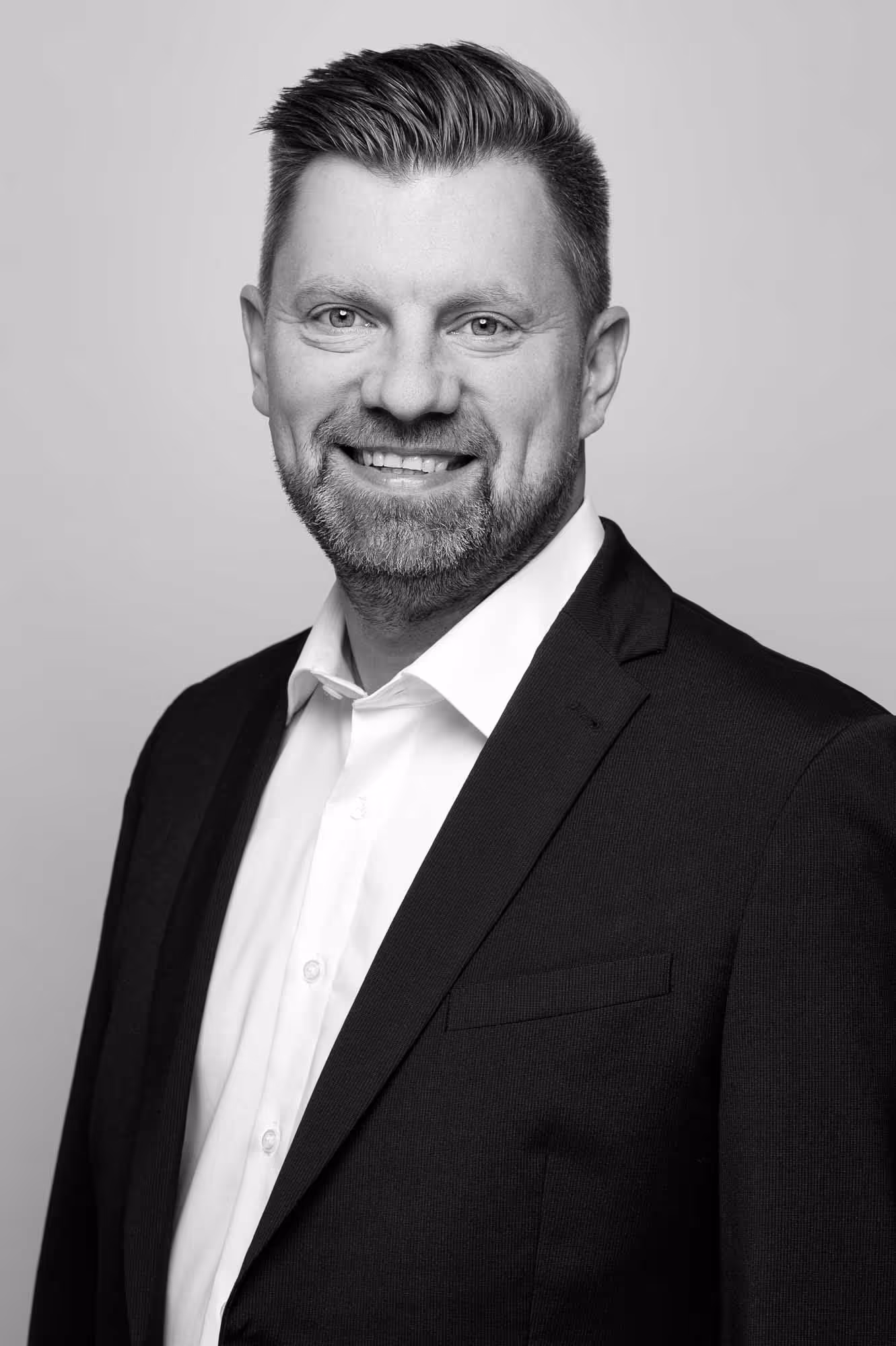 A man in a suit and tie smiles for a photo.