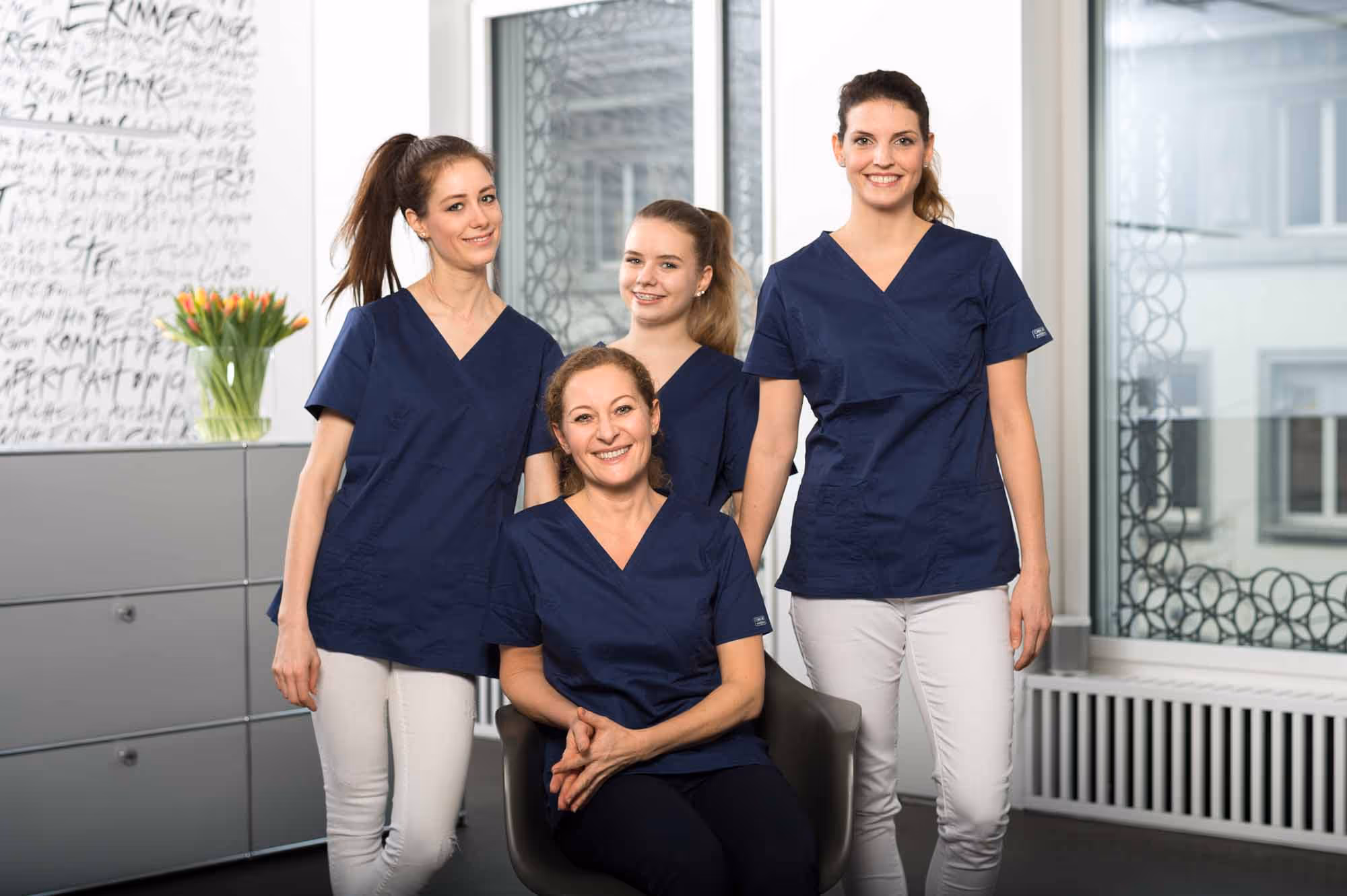 A group of four women in blue gowns pose for a photo.