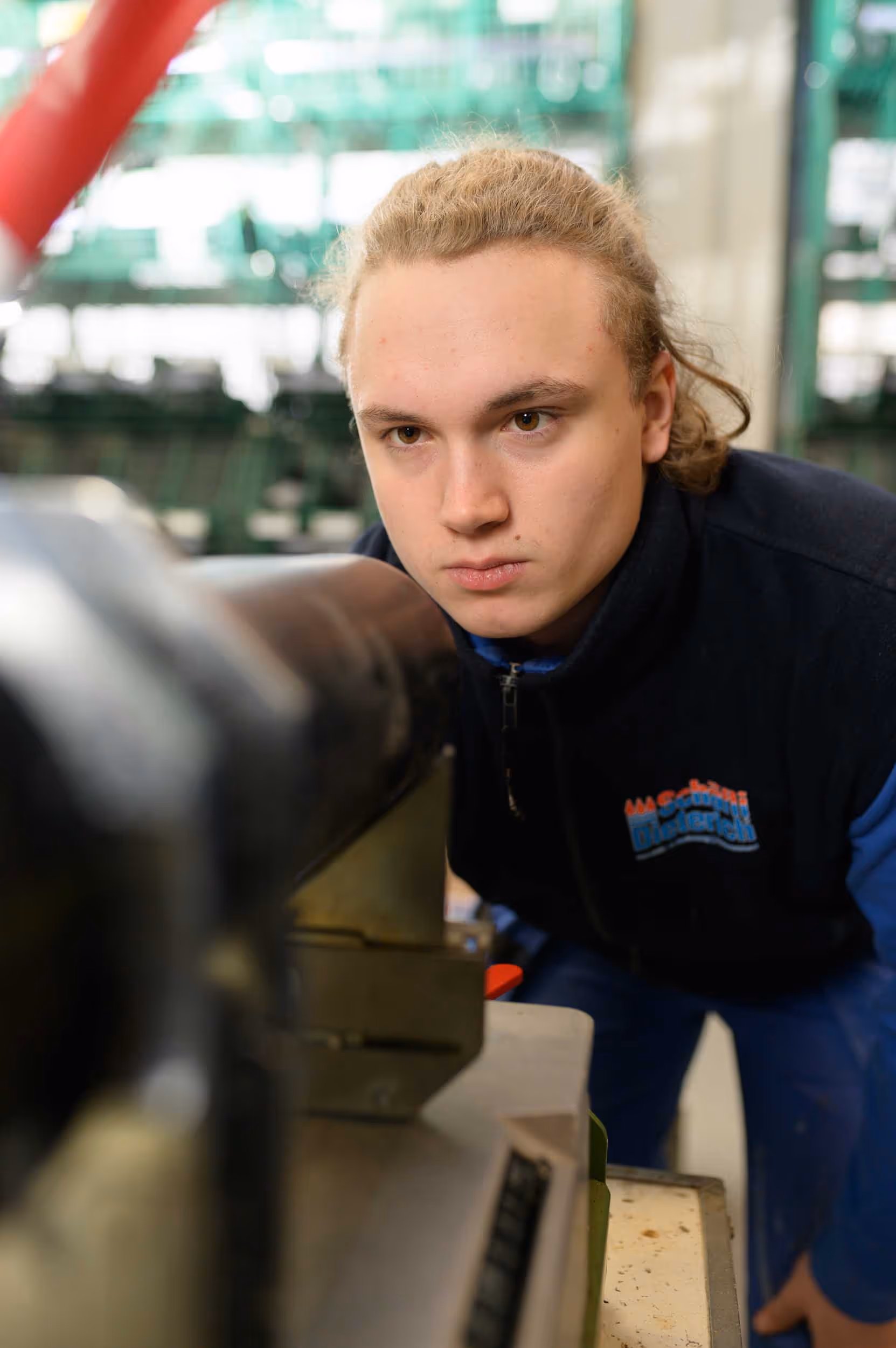 A man in a blue shirt looks at a machine.