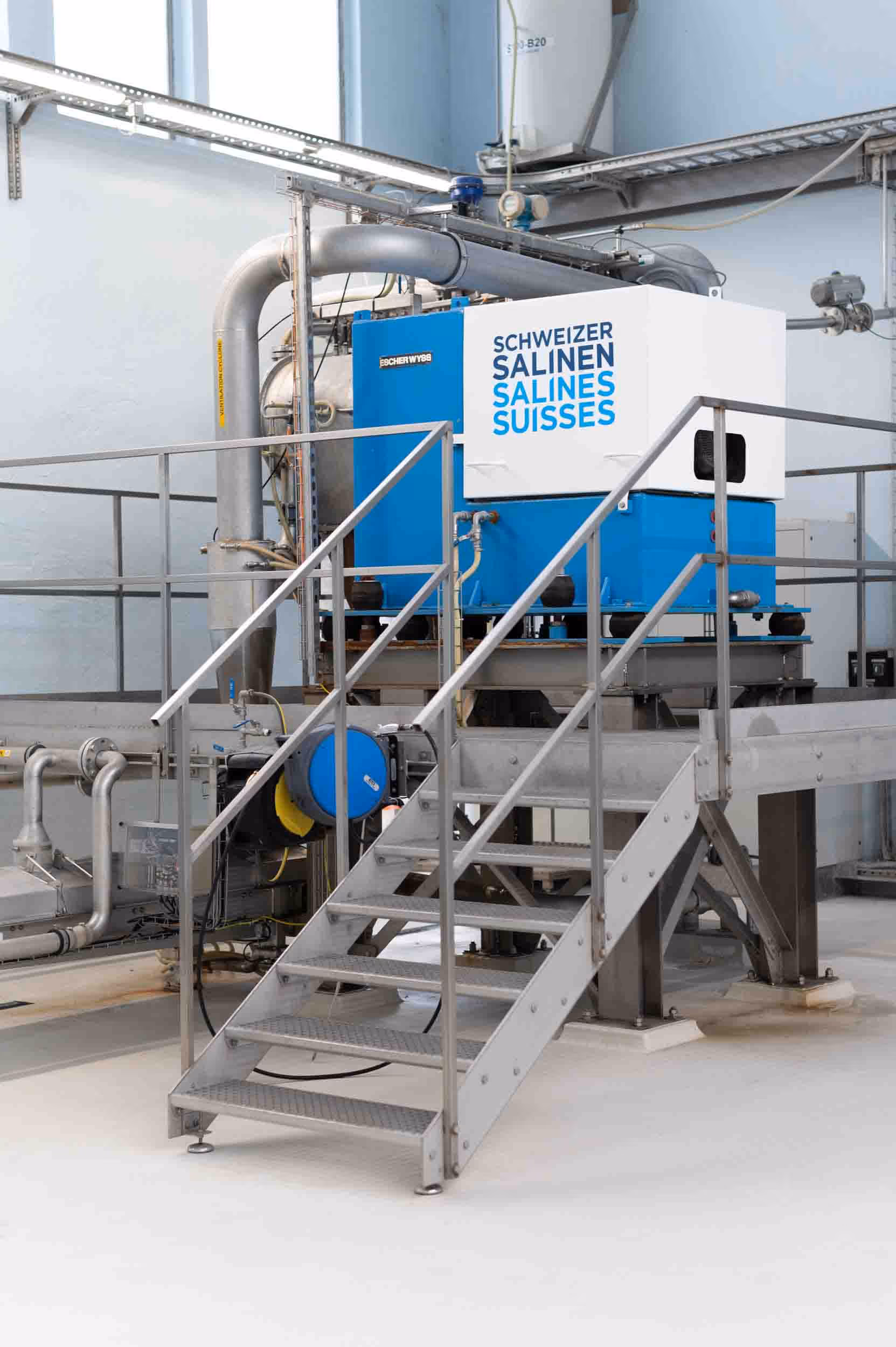 A blue and white machine with the name Schweizer Salinen in a large hall.
